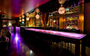 Elegant cocktail lounge with dim lighting, stylish seating, and a bartender preparing signature drinks, creating a luxurious and sophisticated nightlife atmosphere.