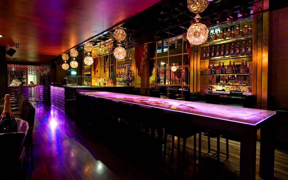 Elegant cocktail lounge with dim lighting, stylish seating, and a bartender preparing signature drinks, creating a luxurious and sophisticated nightlife atmosphere.